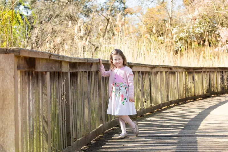 Girl in a white dress walking along a wooden boardwalk through reeds