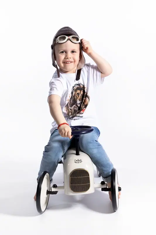 Boy wearing a bandana saluting from a toy car, white background
