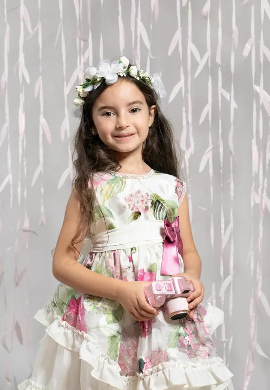 Girl in a floral dress and flower crown in front of a patterned backdrop