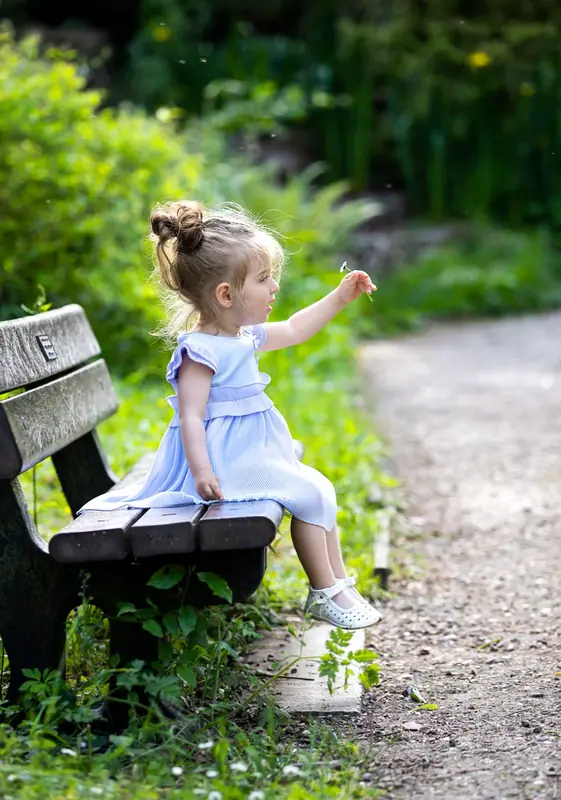 Girl in a white dress sitting on a park bench
