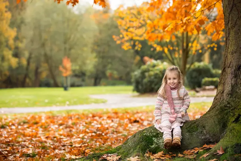 Girl in a white dress standing under an autumn tree