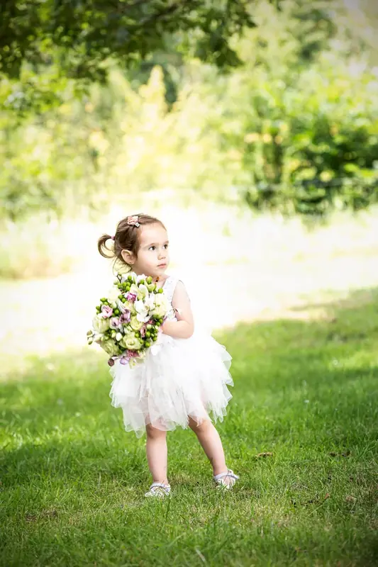 Girl in a white tutu holding flowers on the grass