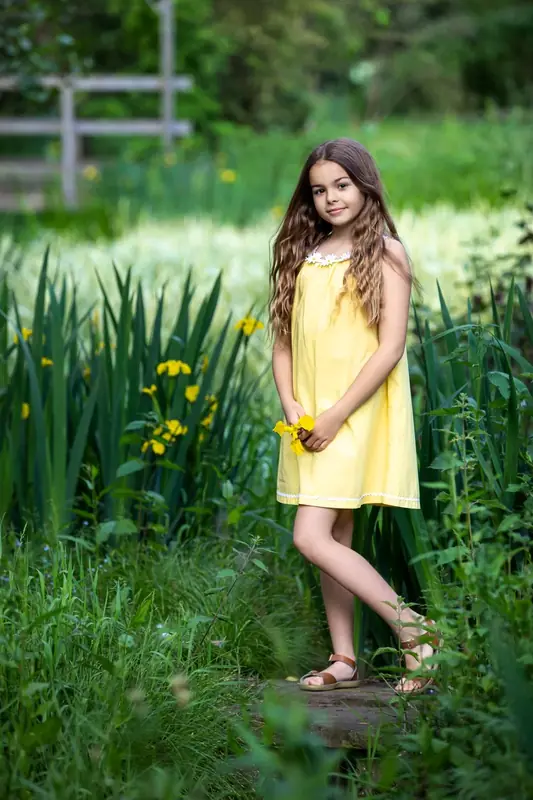 Girl in a yellow dress walking through tall grass