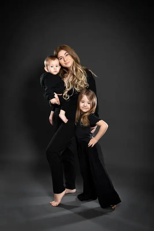 Mother with two daughters dressed in black in a dark studio
