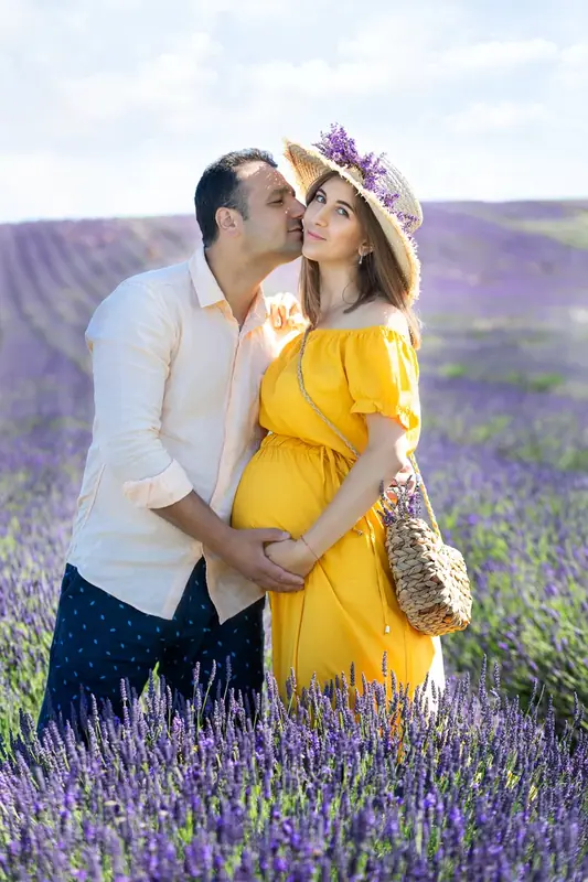 Expectant couple in a lavender field, the woman in a yellow dress and hat