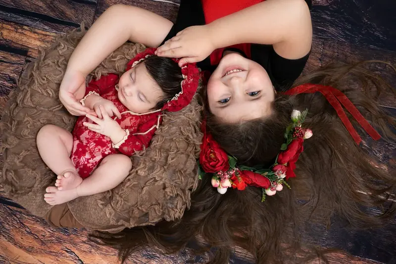 Mother and baby in red lying head to head on a brown rug, seen from above