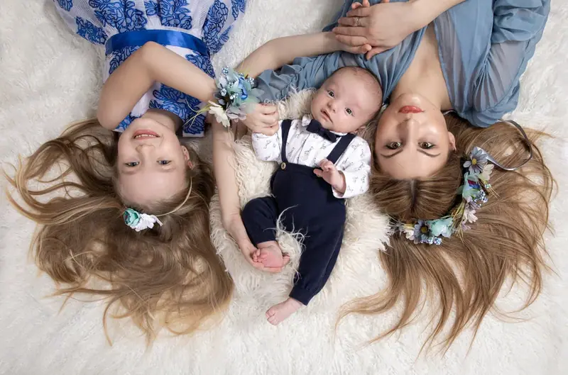 Parents and a young child lying head to head with a newborn, seen from above