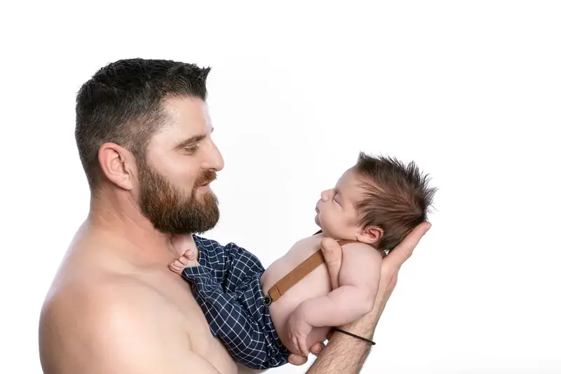 Father holding a newborn up to his face, white background