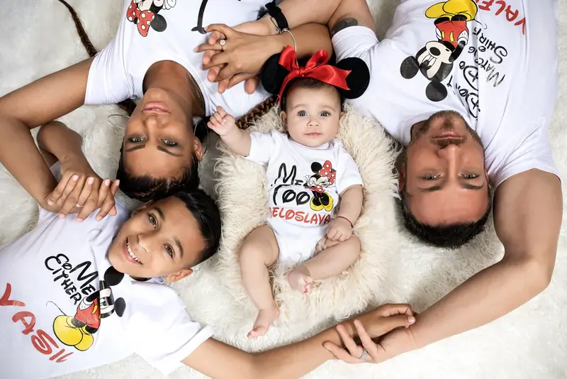 Family of four in matching t-shirts lying head to head with a baby, seen from above