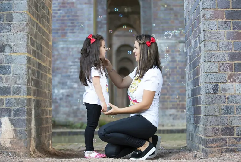 Mother crouching with two daughters in a brick archway