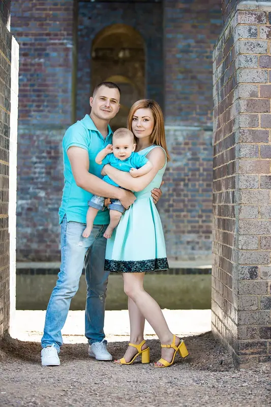 Couple with a young child standing in a brick archway