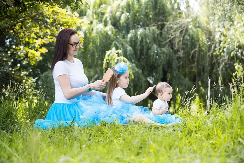 Mother with two young daughters in blue tutus sitting on the grass