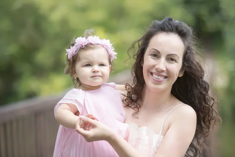 Mother with her toddler daughter in a pink dress and flower headband