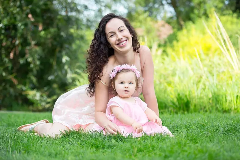 Mother and toddler daughter in pink sitting on the grass