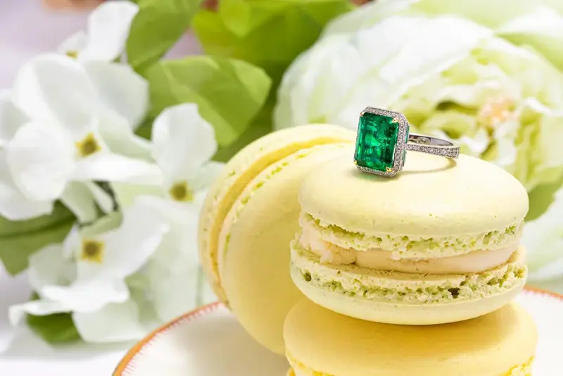 Emerald ring resting on a yellow macaron with white flowers