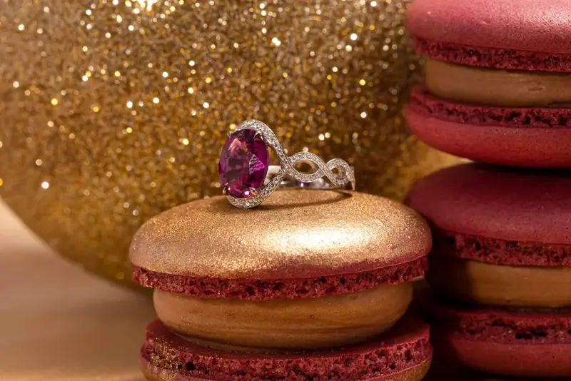 Pink gemstone ring on a gold macaron beside red macarons