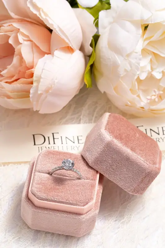 Ring in a pink velvet box in front of pale pink flowers