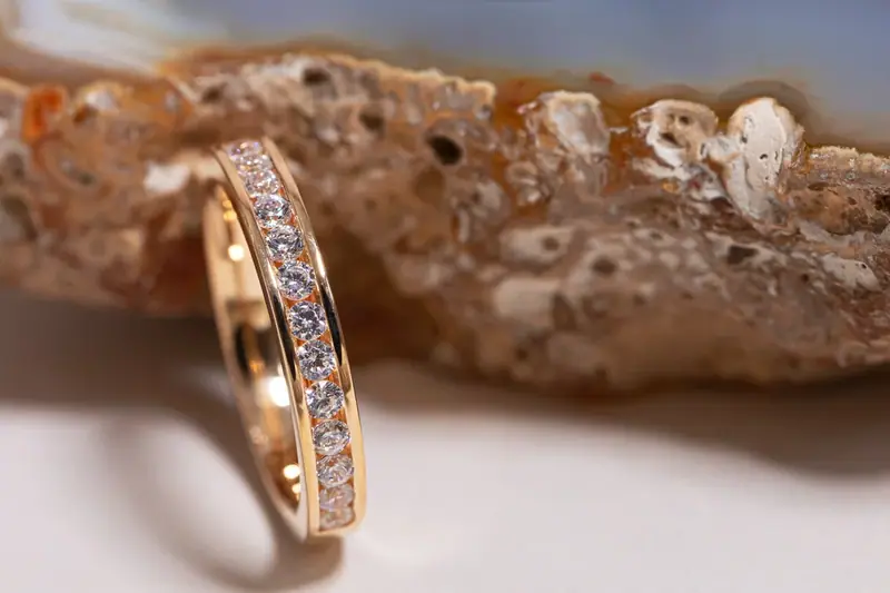 Rose gold diamond band rings resting on coral
