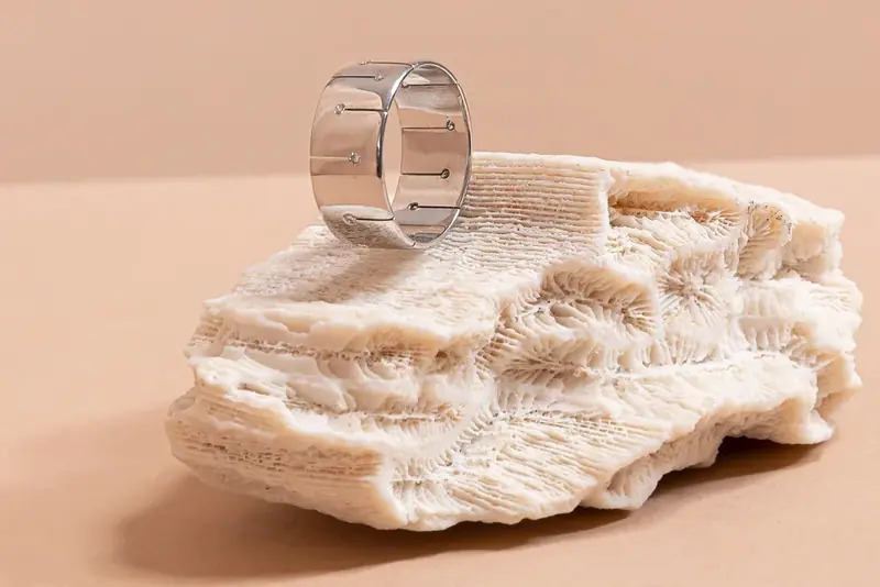 Diamond-set band ring resting on coral, peach background