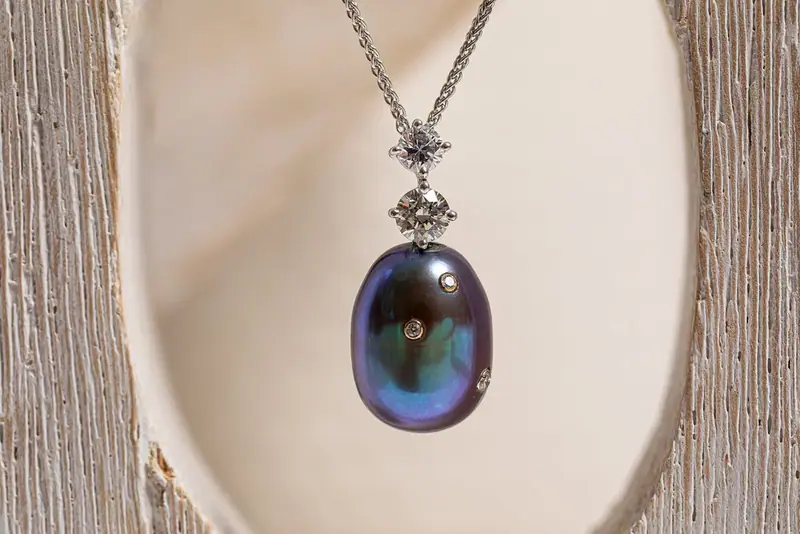 Blue oval pendant on a chain displayed in a white shell