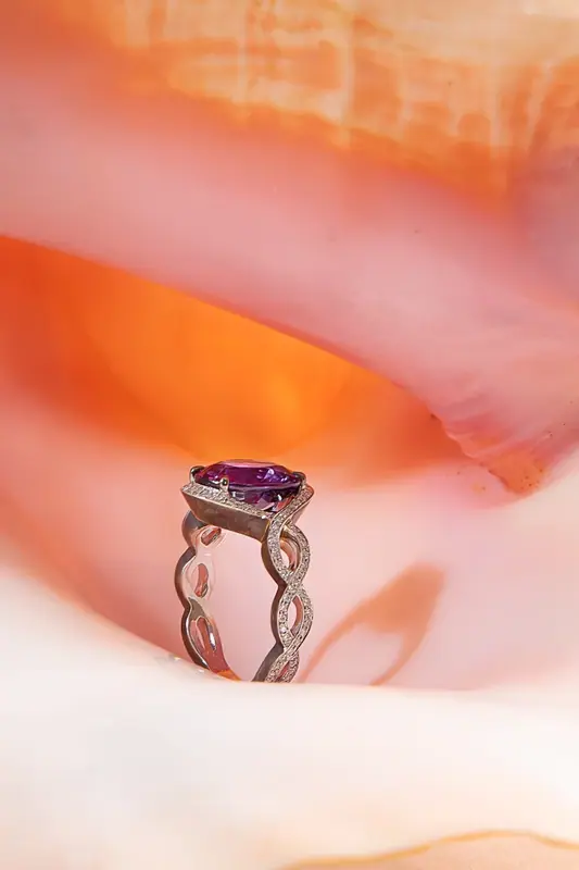 Purple gemstone ring displayed inside a pink shell