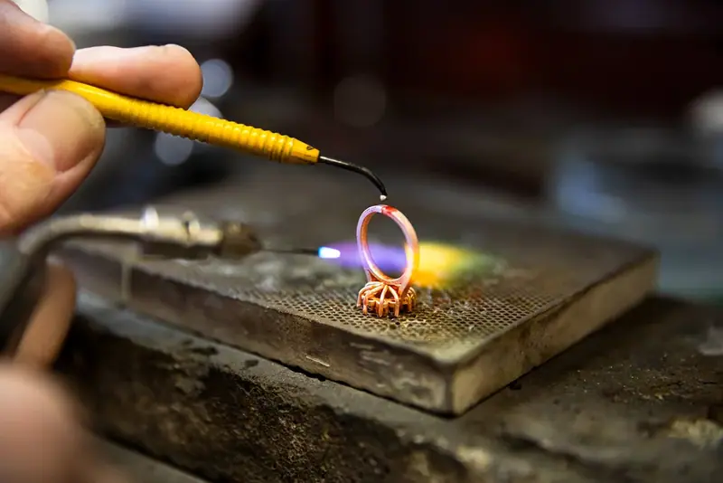 Jeweller soldering a ring with a torch on a workbench