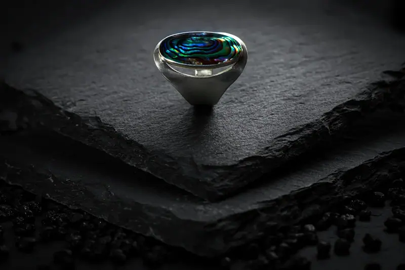 Blue gemstone ring on a black slate against a dark background