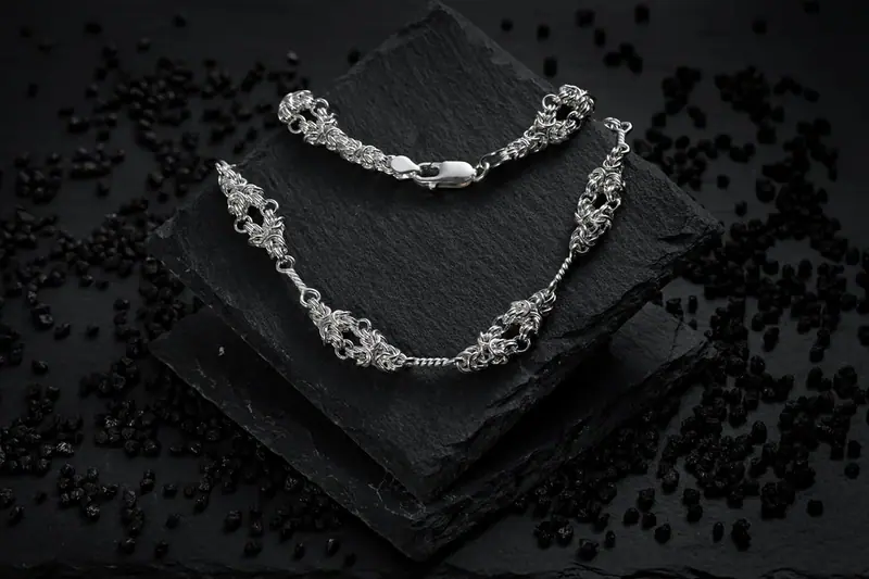 Silver necklace on a black slate against a dark background