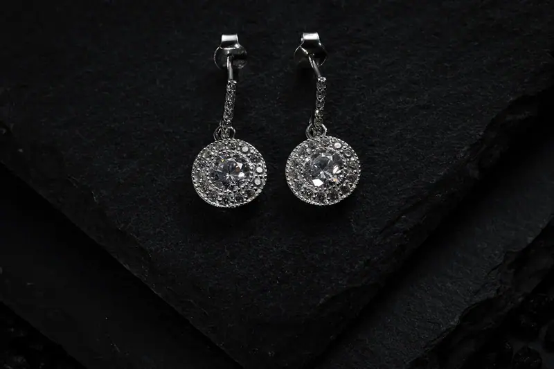 Pair of round diamond drop earrings on black slate
