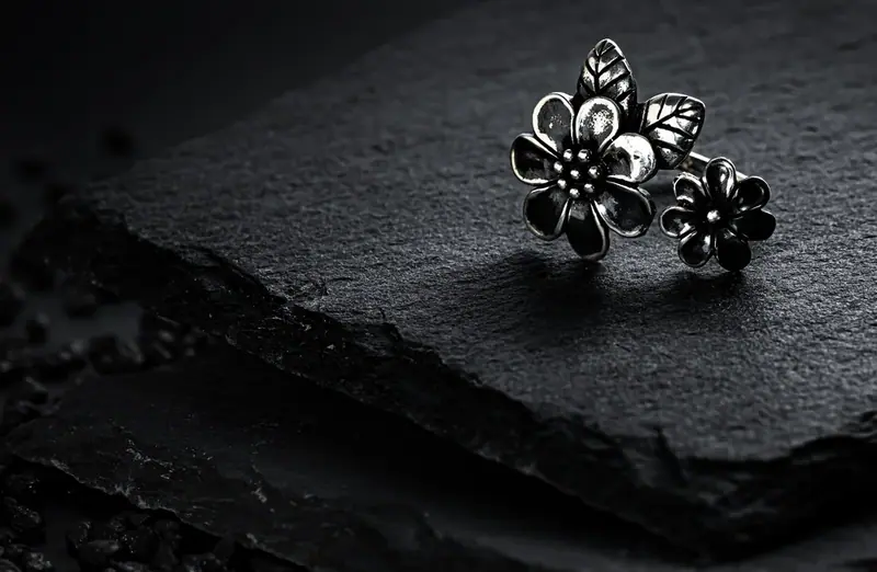 Two silver flower rings on black slate