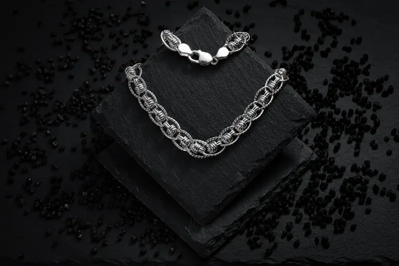 Silver necklace draped over black slate