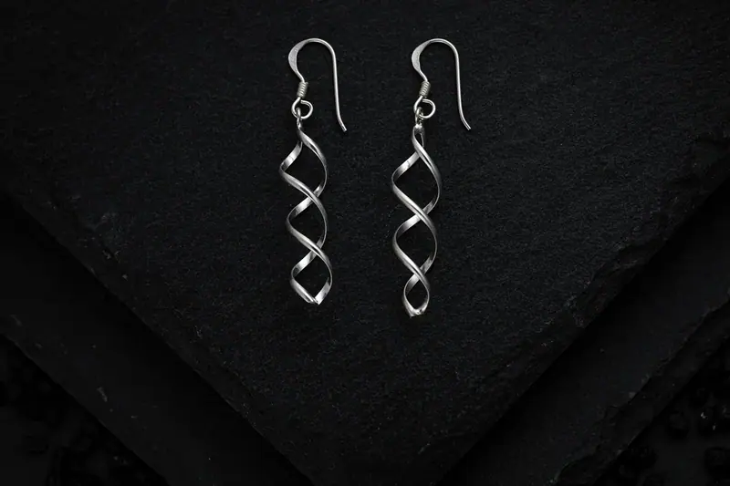 Pair of twisted silver drop earrings on black slate