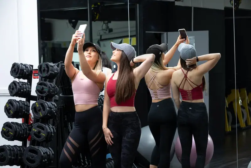 Three women in sportswear photographed from behind in a gym