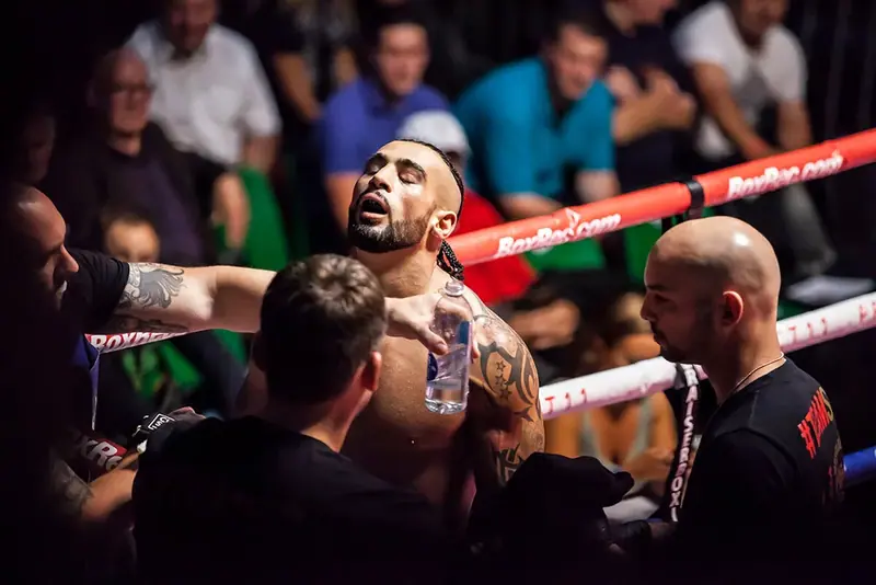 Boxer in the ring surrounded by his team during a bout