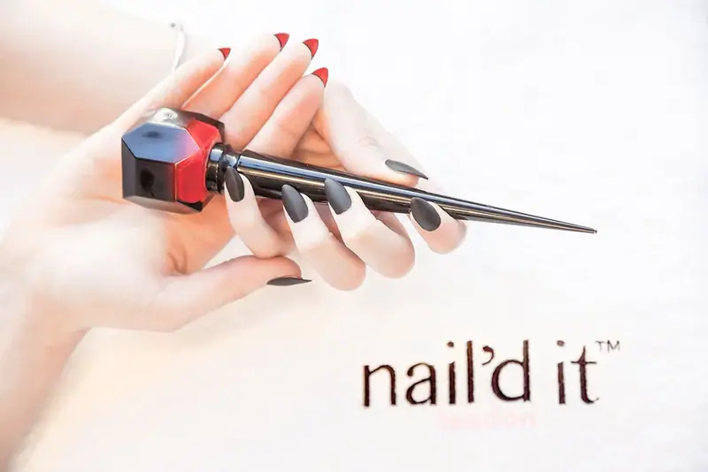 Hand with red nails holding a nail file and polish, with a nail brand logo