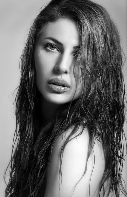Black and white portrait of a woman with long wet hair against a light background