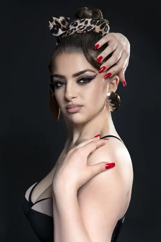 Woman with a leopard-print headscarf and red nails, studio portrait on black