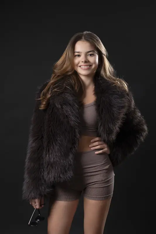 Woman in a fur jacket and shorts standing in a dark studio