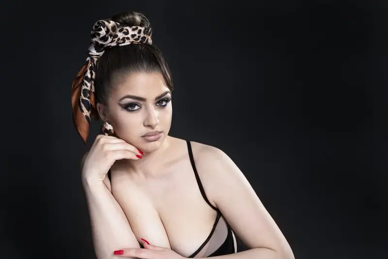 Studio portrait of a woman with a leopard-print headscarf, hand on her cheek