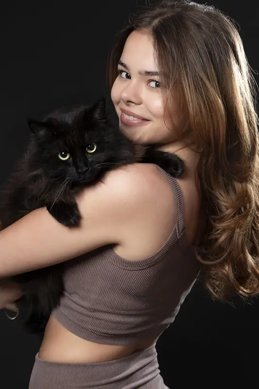 Woman smiling over her shoulder while holding a black cat