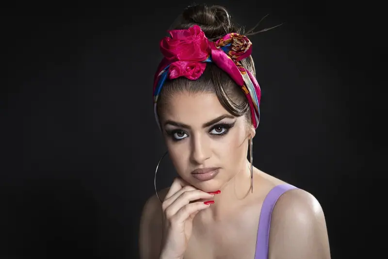 Studio portrait of a woman with a pink flower headband and red nails