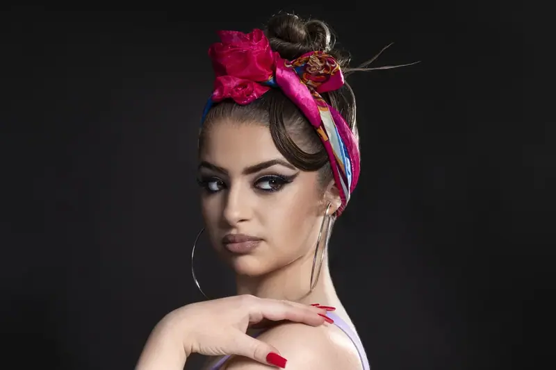 Studio portrait of a woman with a pink flower headband and dramatic make-up
