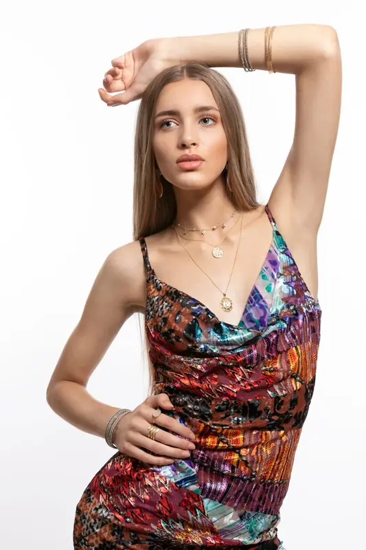 Woman in a colourful patterned dress with one arm raised, white background