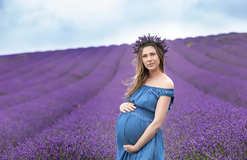 Expectant mother in a blue off-the-shoulder gown standing in a lavender field