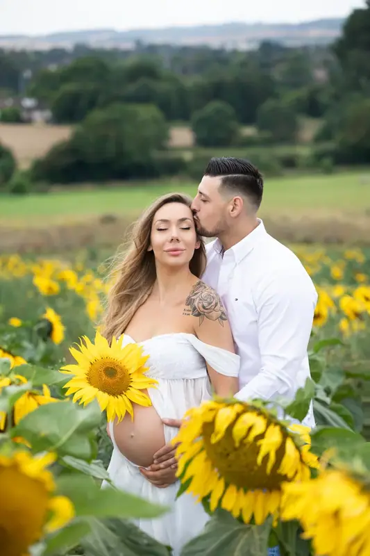 Expectant couple embracing in a field of sunflowers