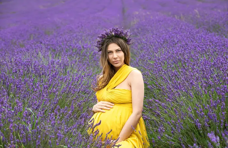 Expectant mother in a yellow dress and flower crown in a lavender field
