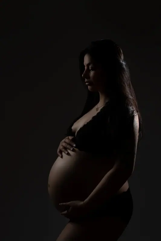 Silhouette of an expectant mother in profile against a dark background