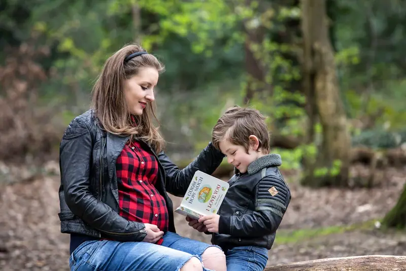 Expectant couple sitting together in a wood, the man holding an ultrasound picture