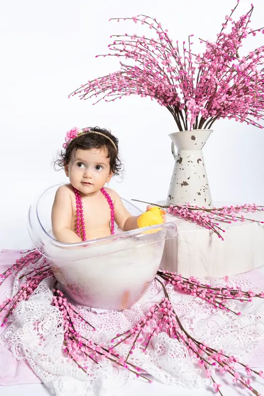 Baby sitting in a milk bath with pink blossom branches