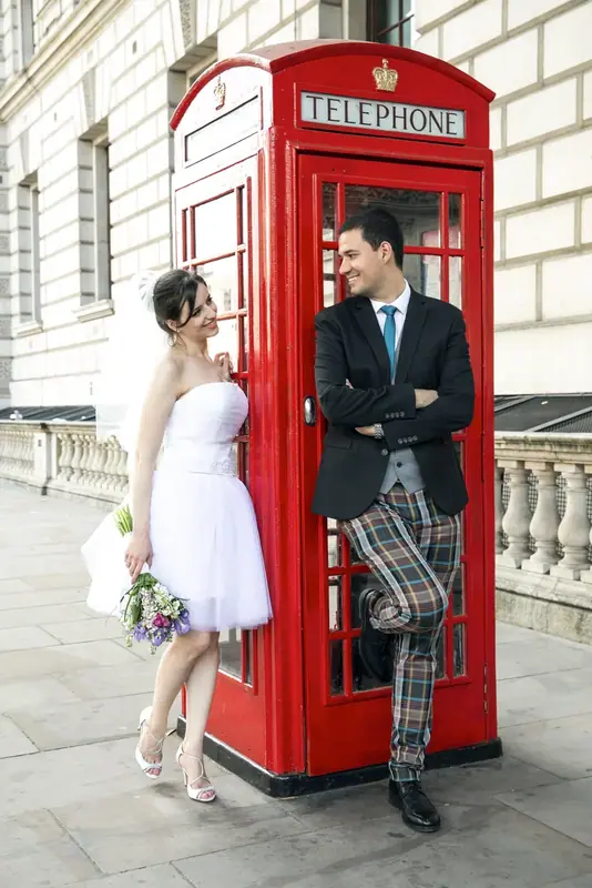 Bride and groom posing in a red London telephone box